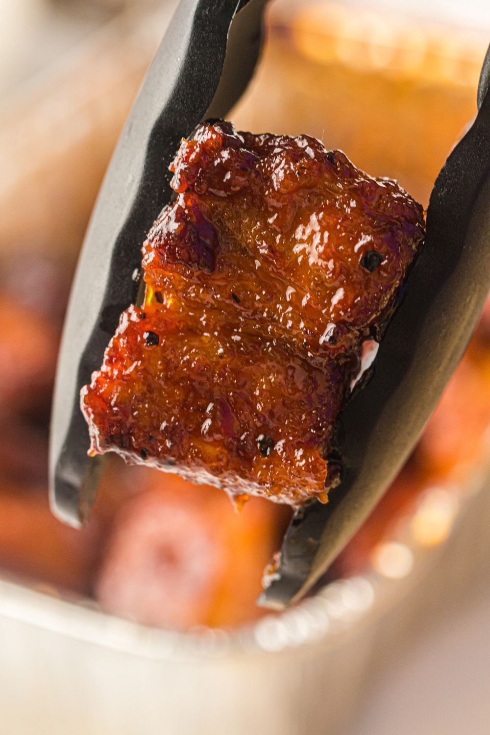 tong holding a piece of burnt ends