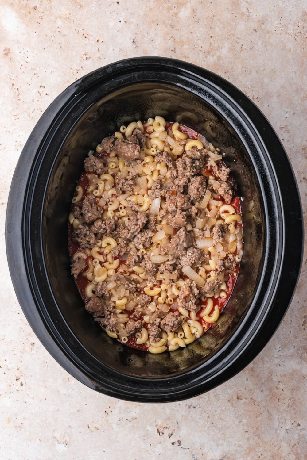 Slow Cooker Pizza Casserole on counter being assembled