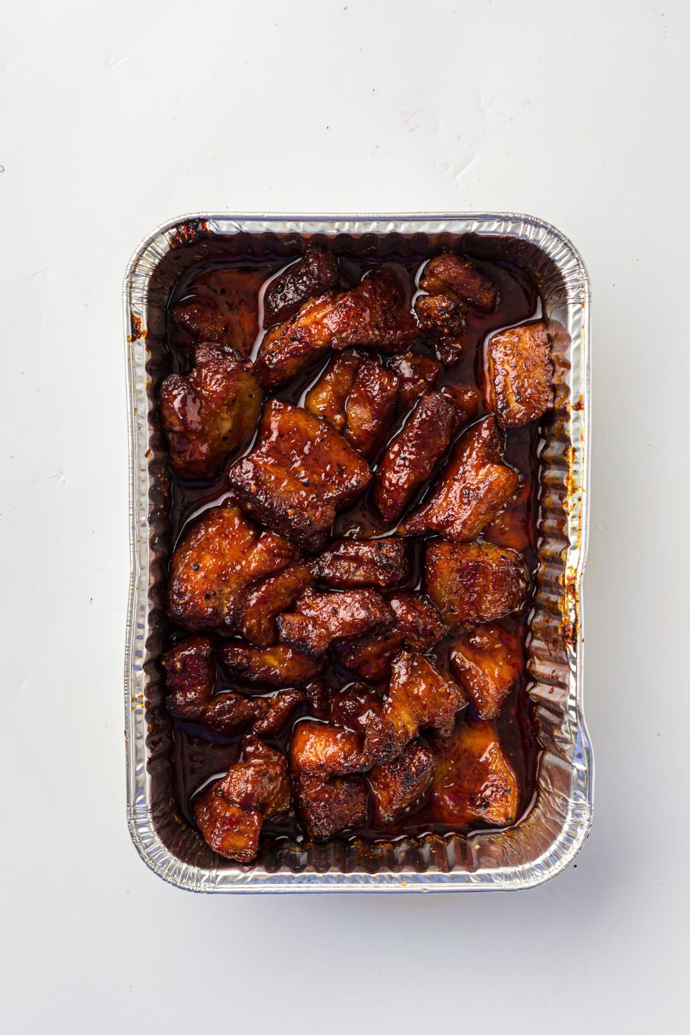 Smoked Pork Belly Burnt Ends in a foil container sitting on a table