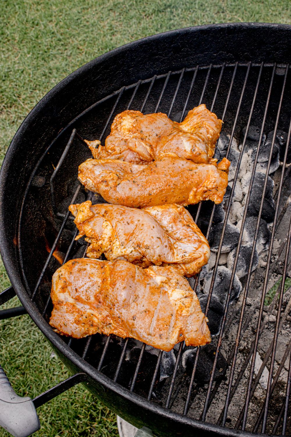 raw chicken placed on a charcoal grill 