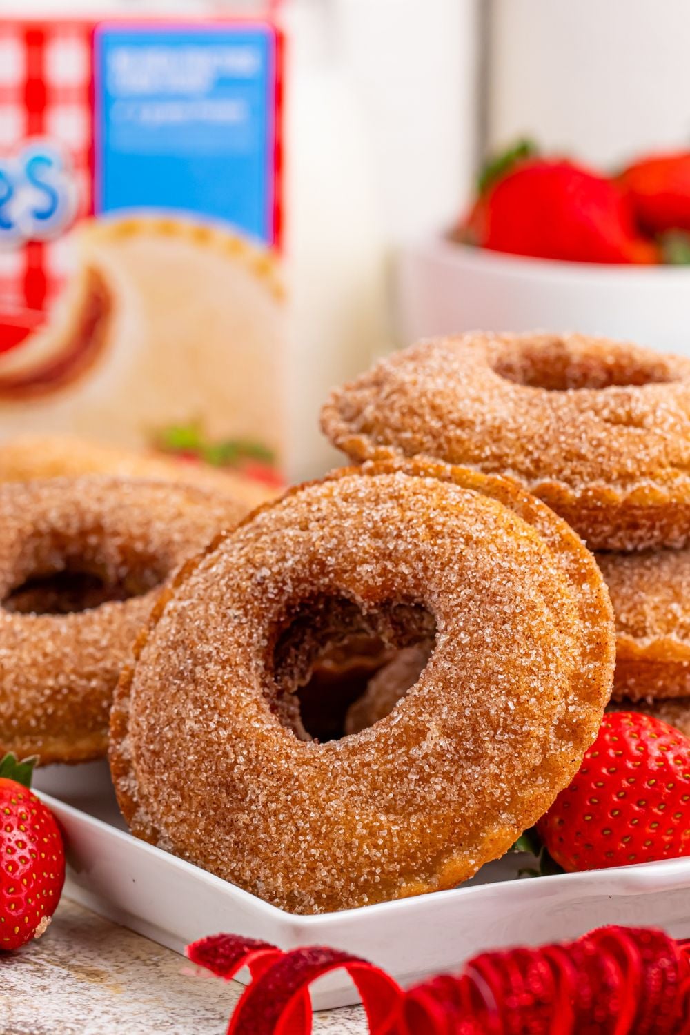 close up of Fried Strawberry Uncrustables on table with hearts cut out in center and box of sandwiches in background 