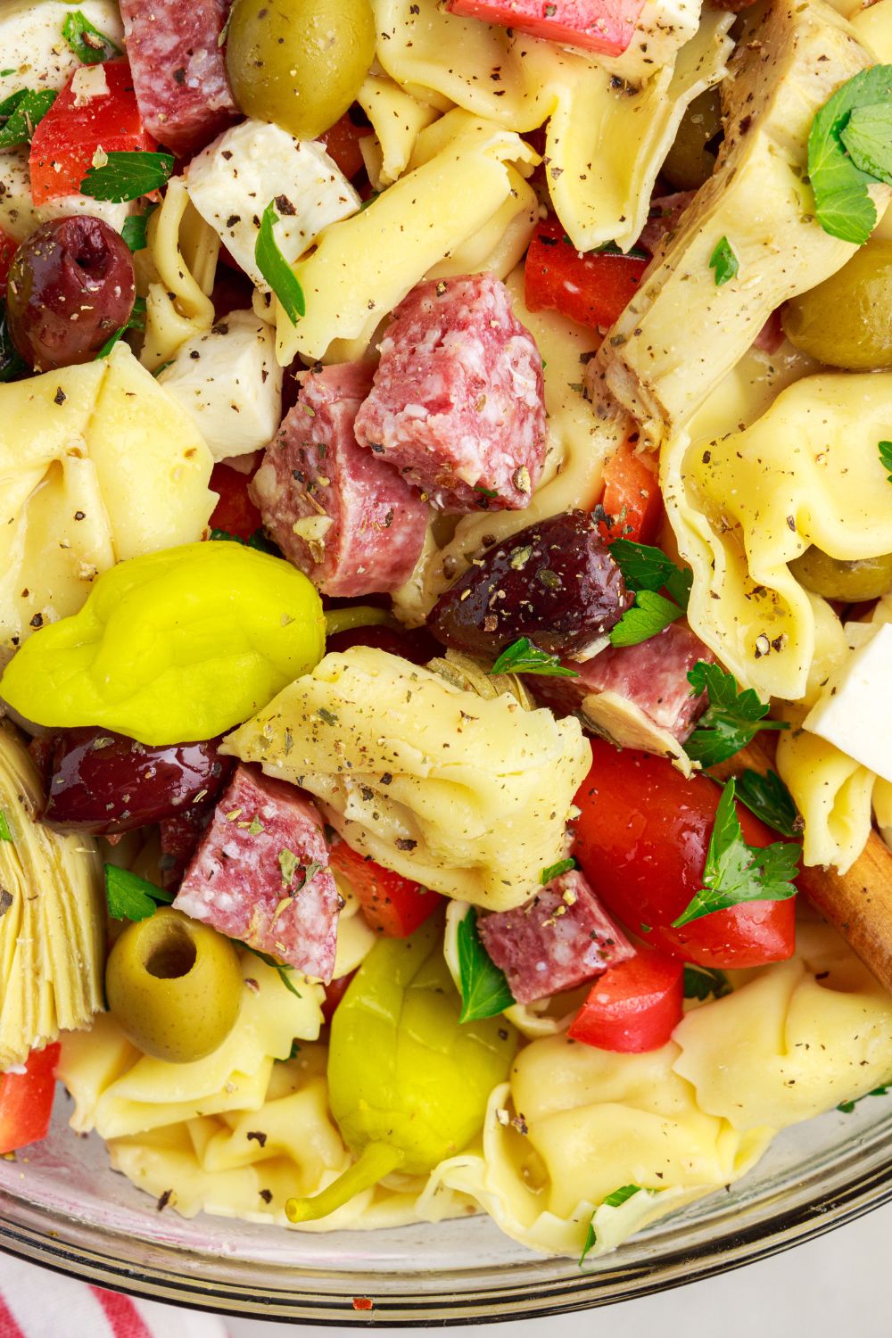 Antipasto Tortellini Pasta Salad in a bowl with a close up on tortellini and other ingredients 