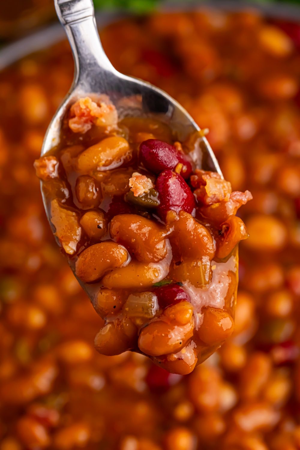 Crockpot bourbon baked beans in a bowl with a spoon scooping some beans out