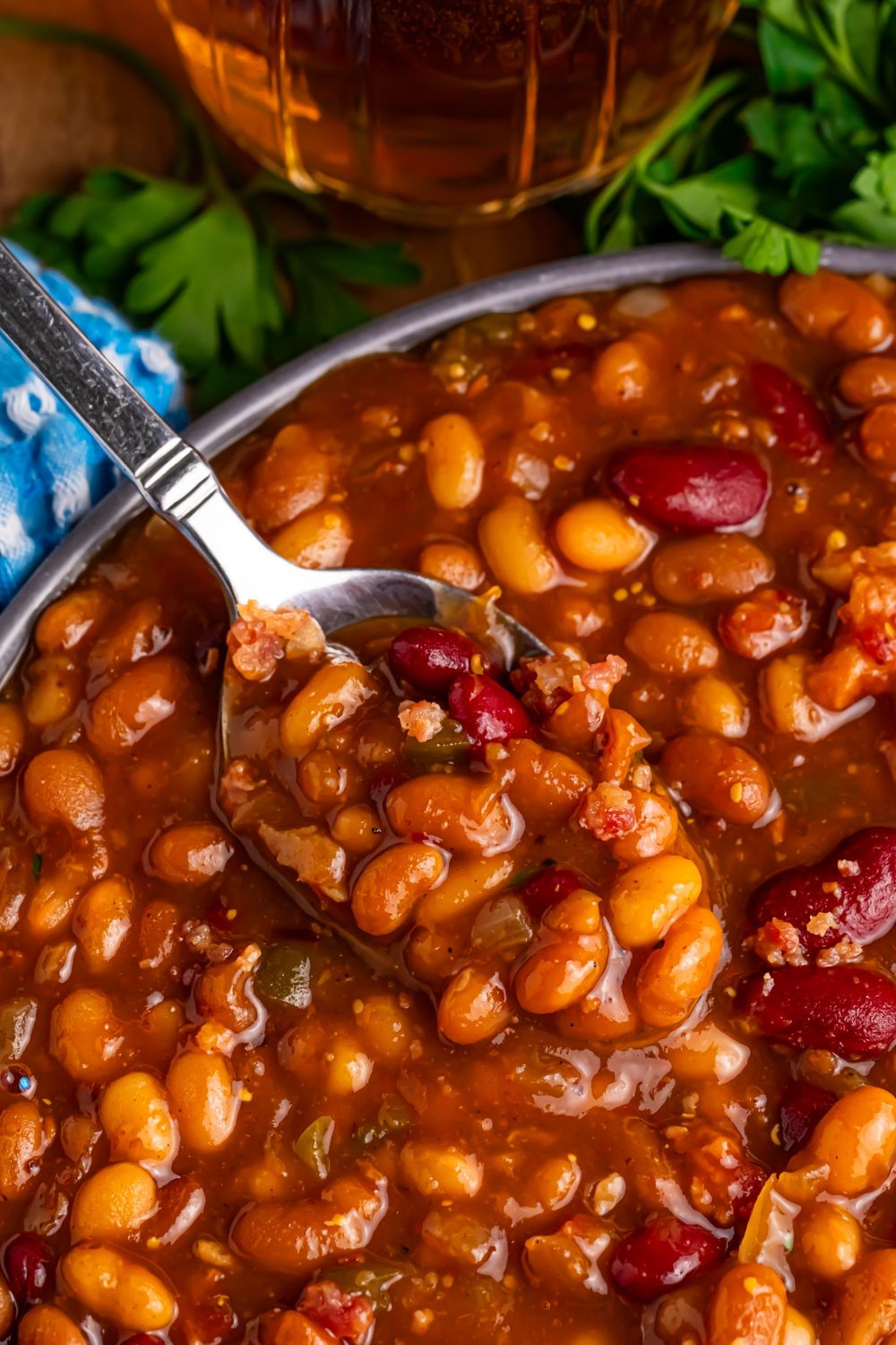 Crockpot bourbon baked beans in a bowl with a spoon scooping some out of bowl