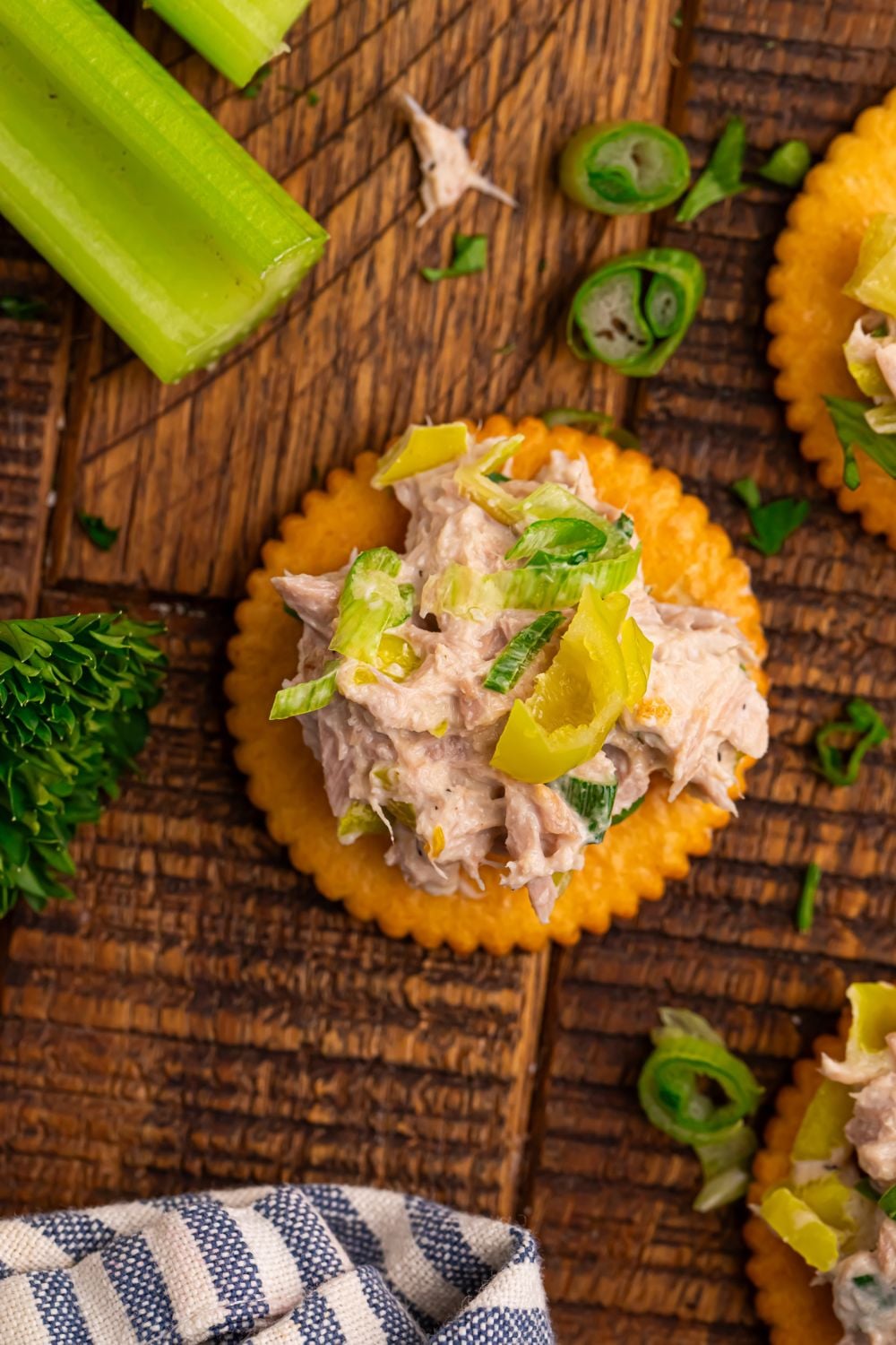 looking down at table to see celery, herbs, and a crackers with Pepperoncini Ranch Tuna Salad piled on top