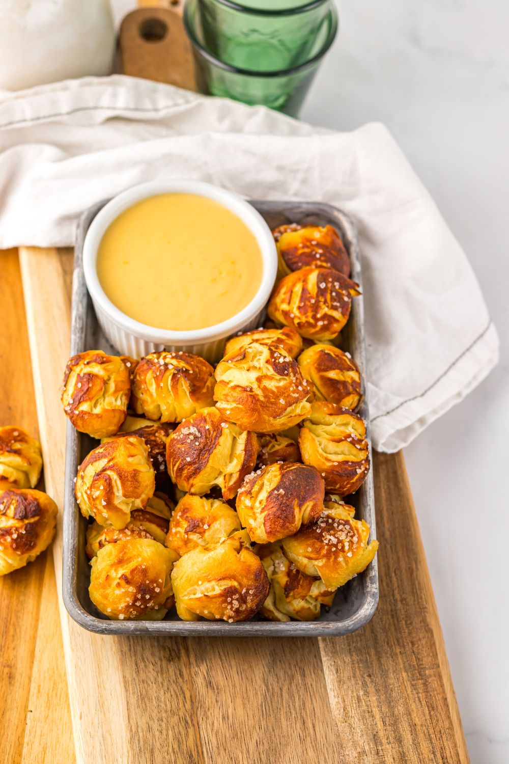 Easy Biscuit Pretzel Bites with Cheese Sauce on a tray sitting on table with a towel to side