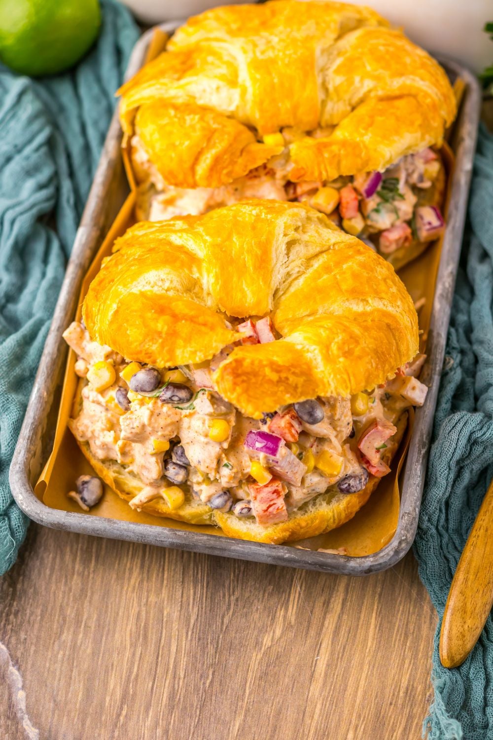 overhead look of table with Creamy Taco Chicken Salad sandwiches on plate with a towel on bottom of pan