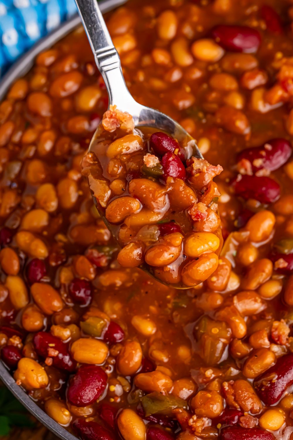 Crockpot bourbon baked beans in a bowl with a spoon scooping some out of bowl