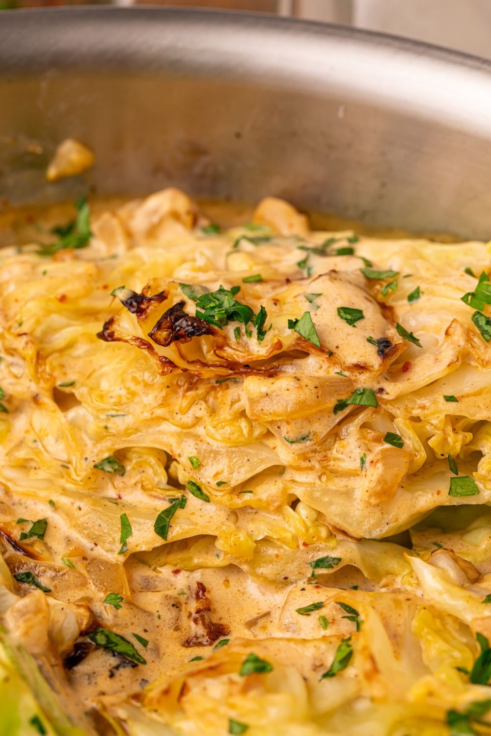 Creamy Garlic Parmesan Cabbage in a pan with some chopped parsley on top 