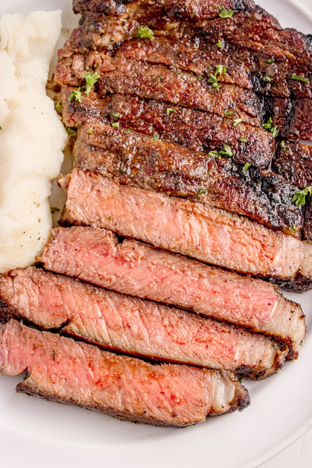 overhead look of sliced steak on plate with mashed potatoes to the side of plate