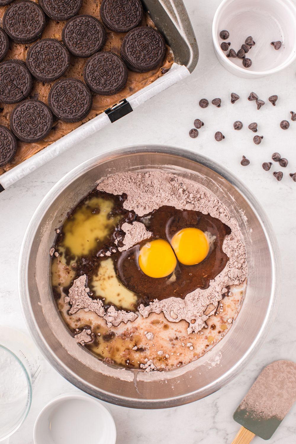 Slutty Brownies being assembled on table with a brownie batter in a bowl on table 