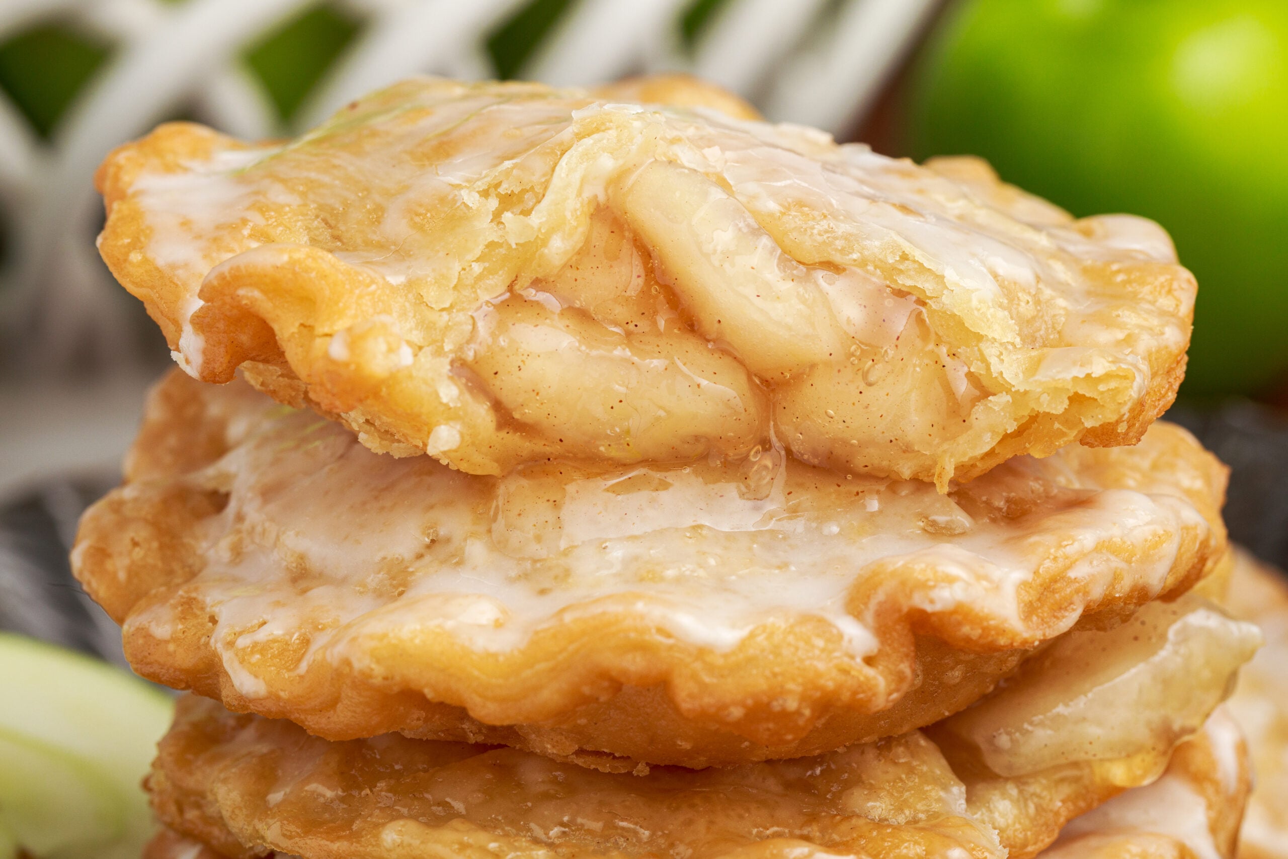 Deep Fried Apple Hand Pies stacked on top of each other with one that has a bite taken out of it