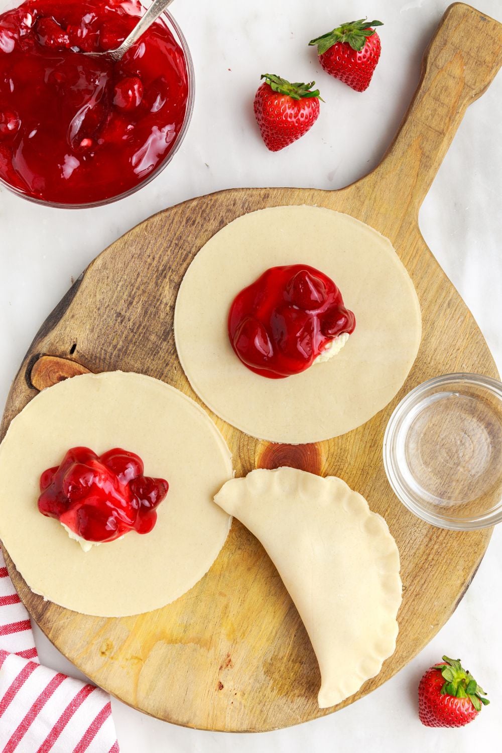 assembling pie filling on top of pie crust to make strawberry hand pies
