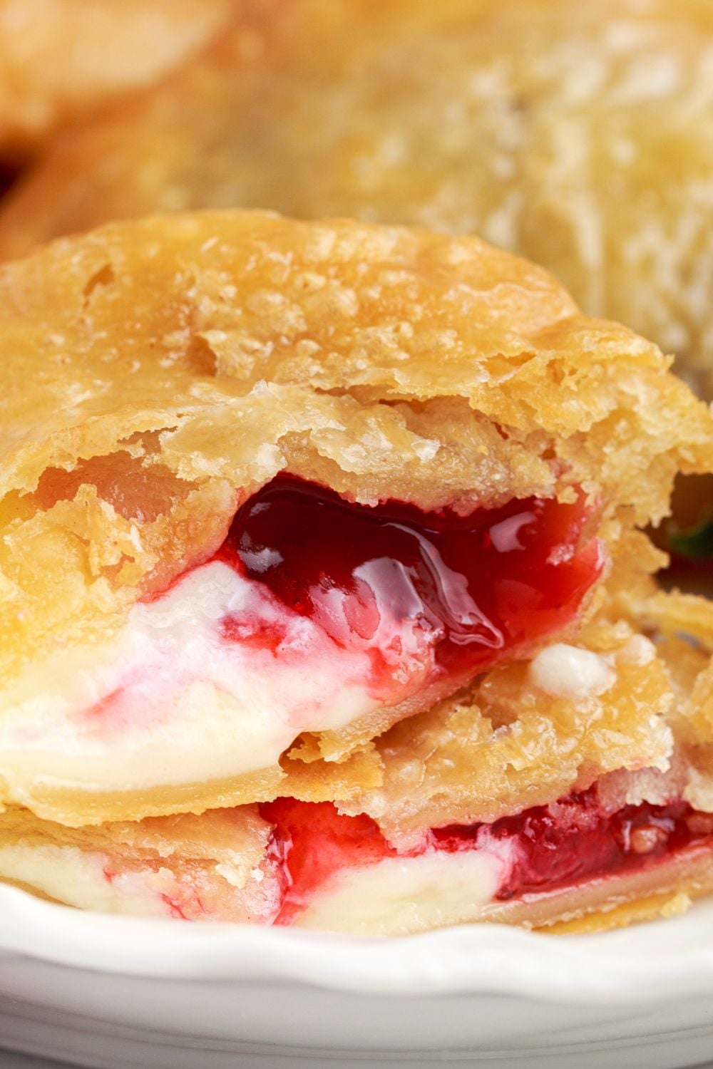 Deep Fried Strawberry Cheesecake Pies on plate with one torn apart to show the creamy filling