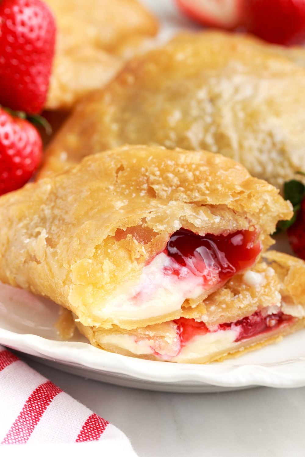 Deep Fried Strawberry Cheesecake Pie cut in half and placed on table to show the filling with strawberries to the side