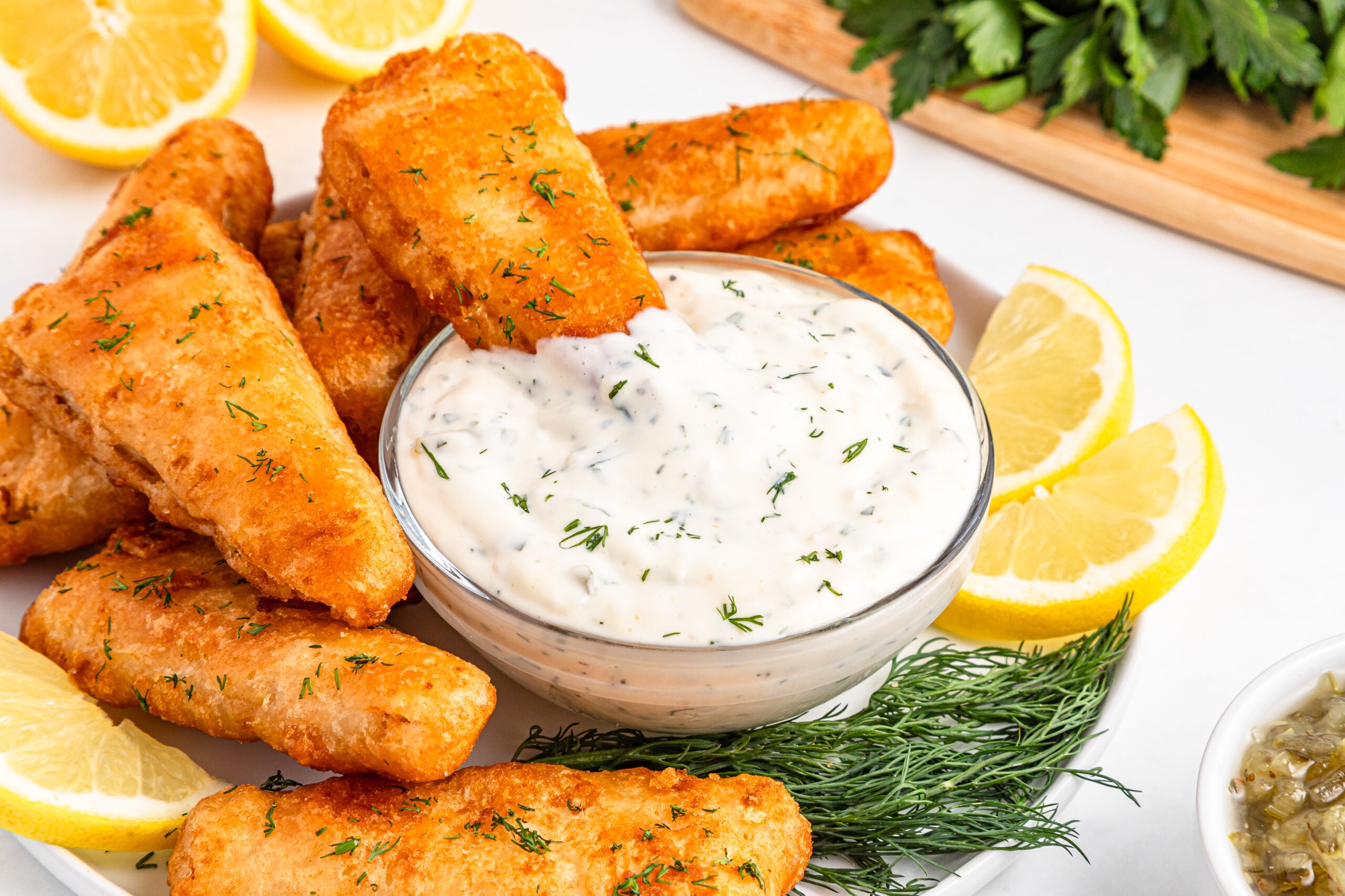 Fish being dipped into a bowl of tartar sauce