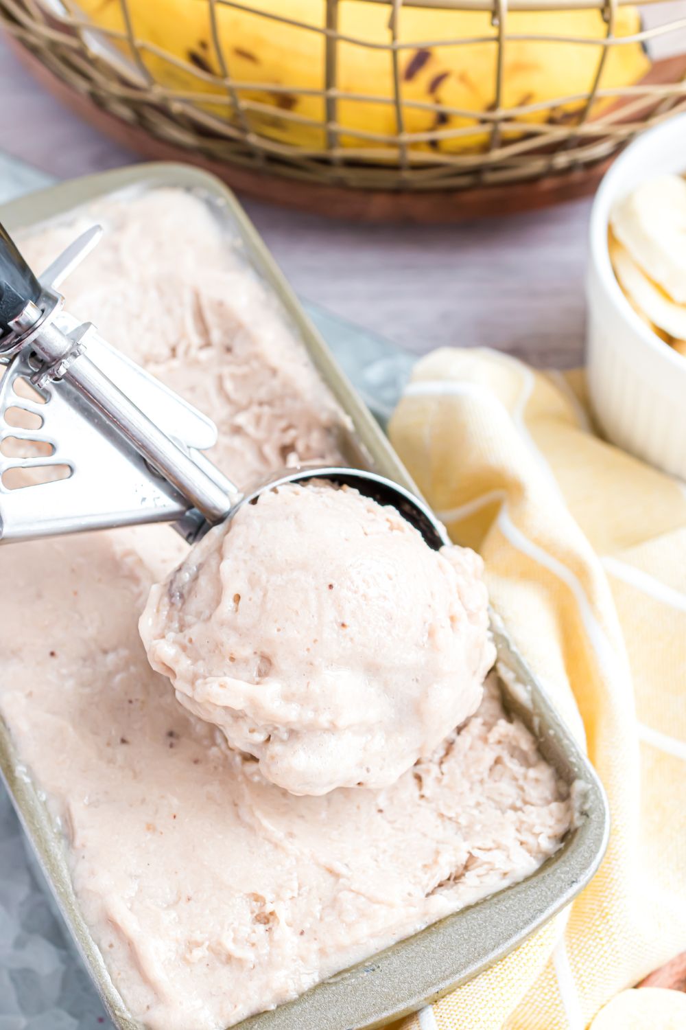 Banana Ice Cream in a loaf pan with an ice cream scoop full of ice cream