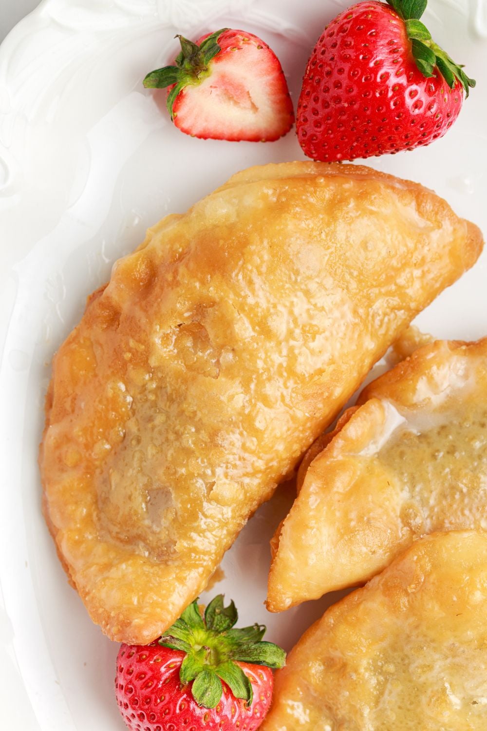 Deep Fried Strawberry Cheesecake Pie on plate with more scattered to side