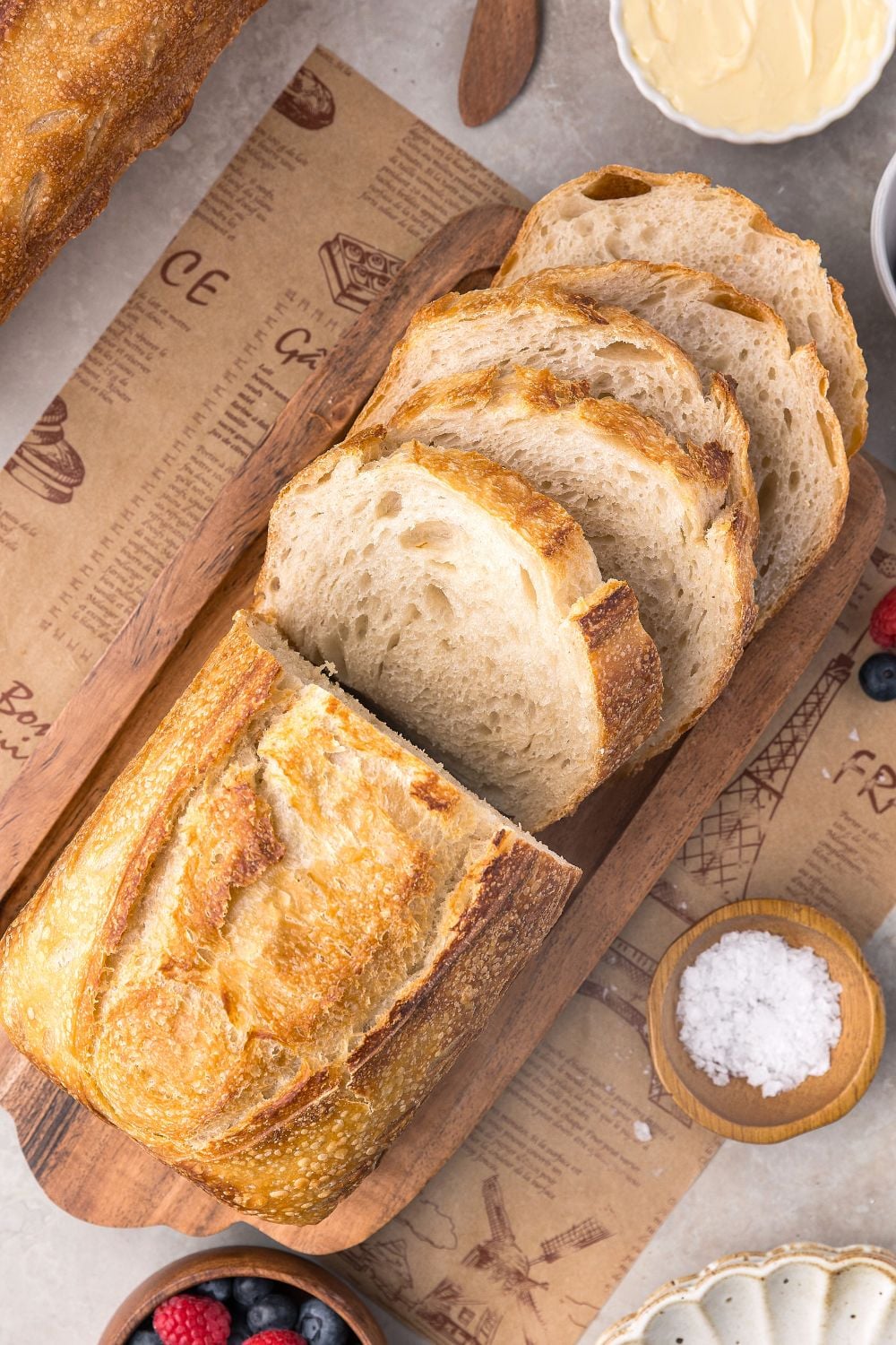 Homemade Sourdough Bread sliced on tray with some butter and salt in small bowls to side