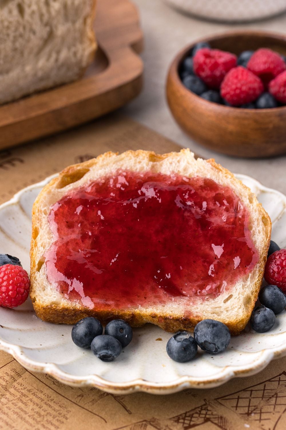 Homemade Sourdough Bread sliced on plate with jam, and berries around it 