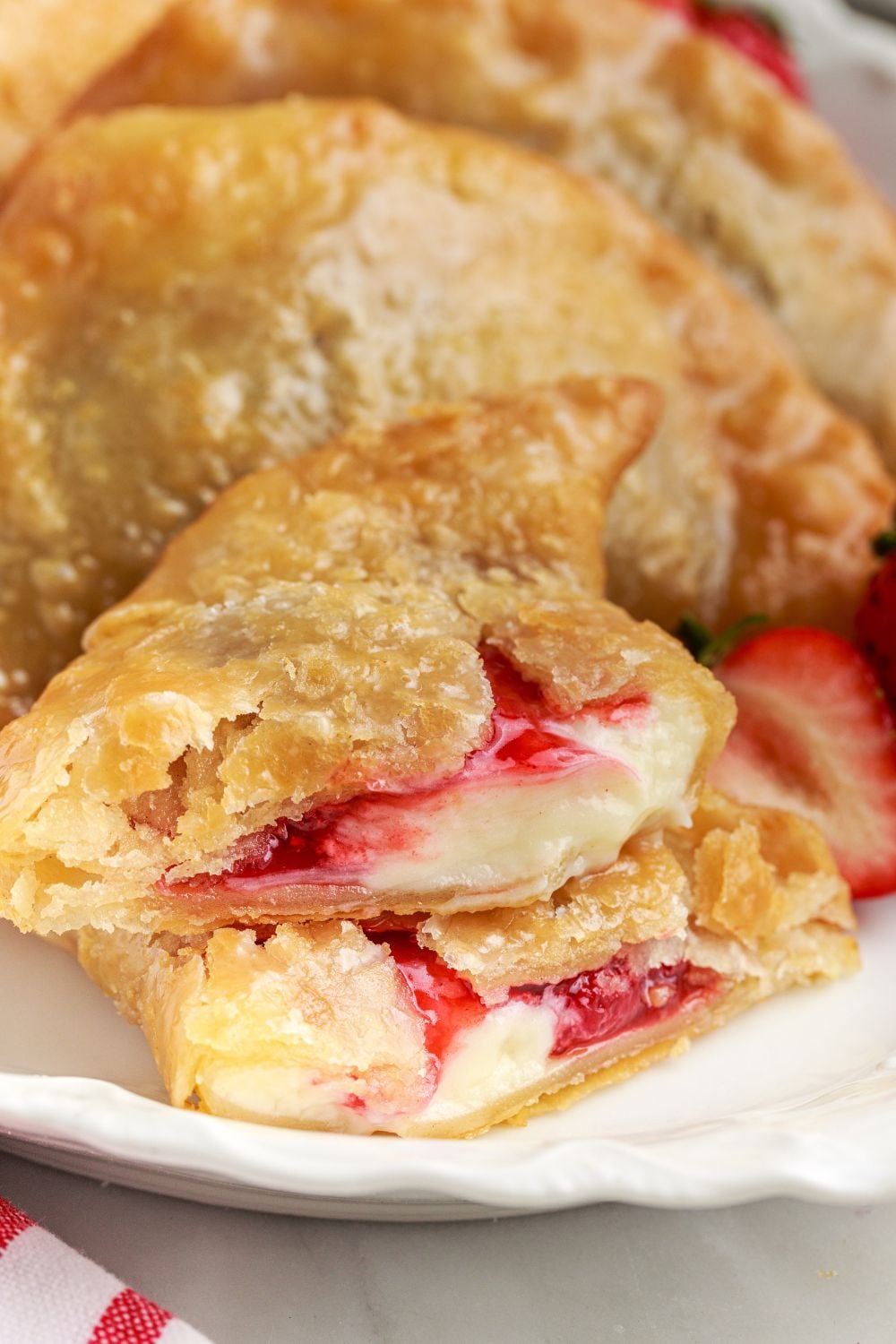 Deep Fried Strawberry Cheesecake Pies on plate with one cut in half to see the filling