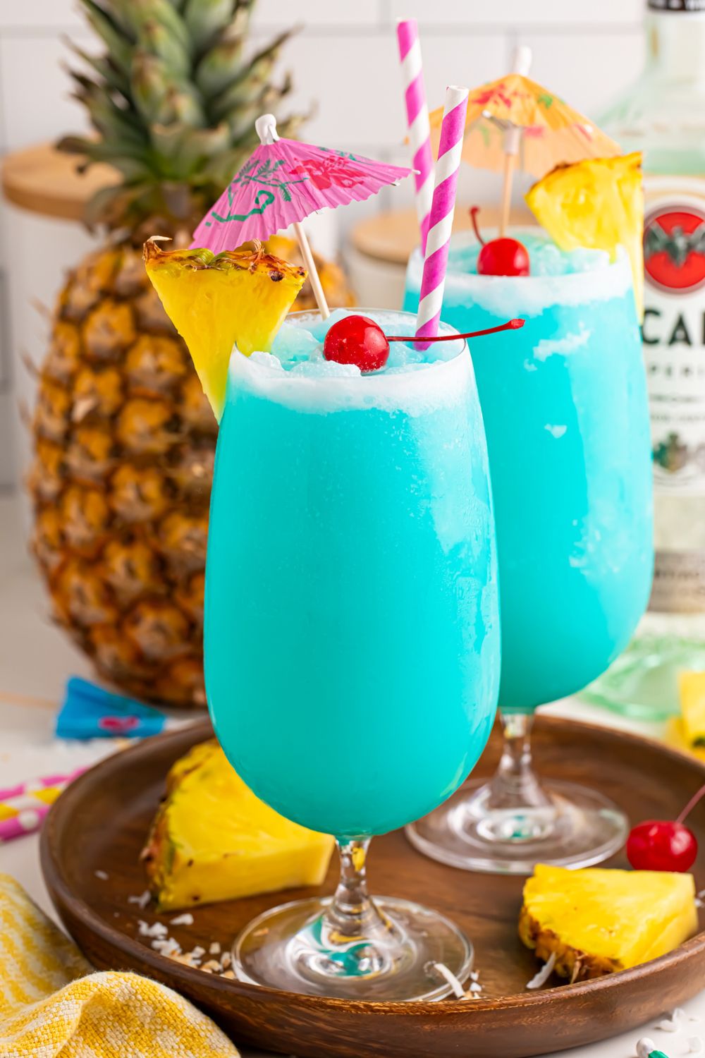 Fruity tropical rum cocktails on table with some pineapple wedges and cherries sitting on serving tray