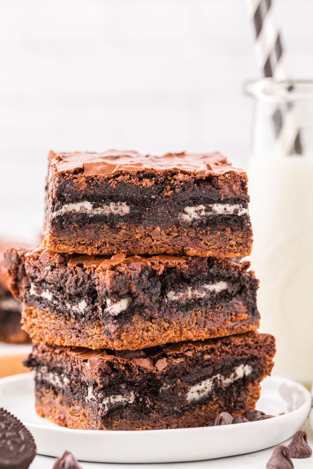 Slutty Brownies stacked on top of one another with a glass of milk behind it on table 