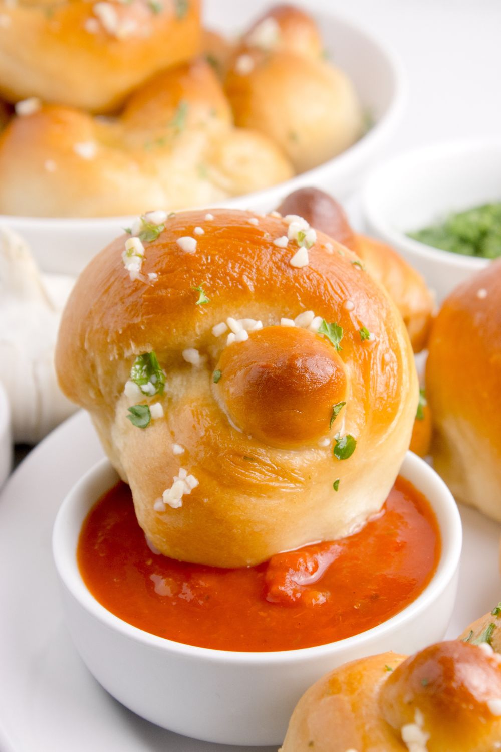 garlic knots dipped in marinara sauce sitting on table 
