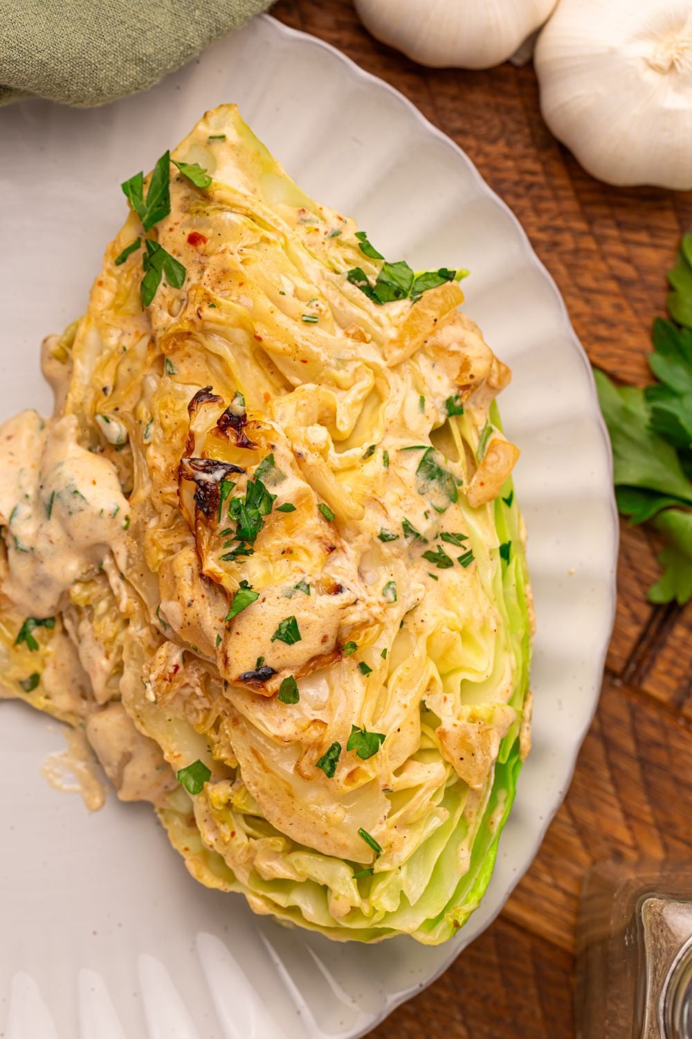 Creamy Garlic Parmesan Cabbage wedge on a plate topped with a creamy garlic sauce 