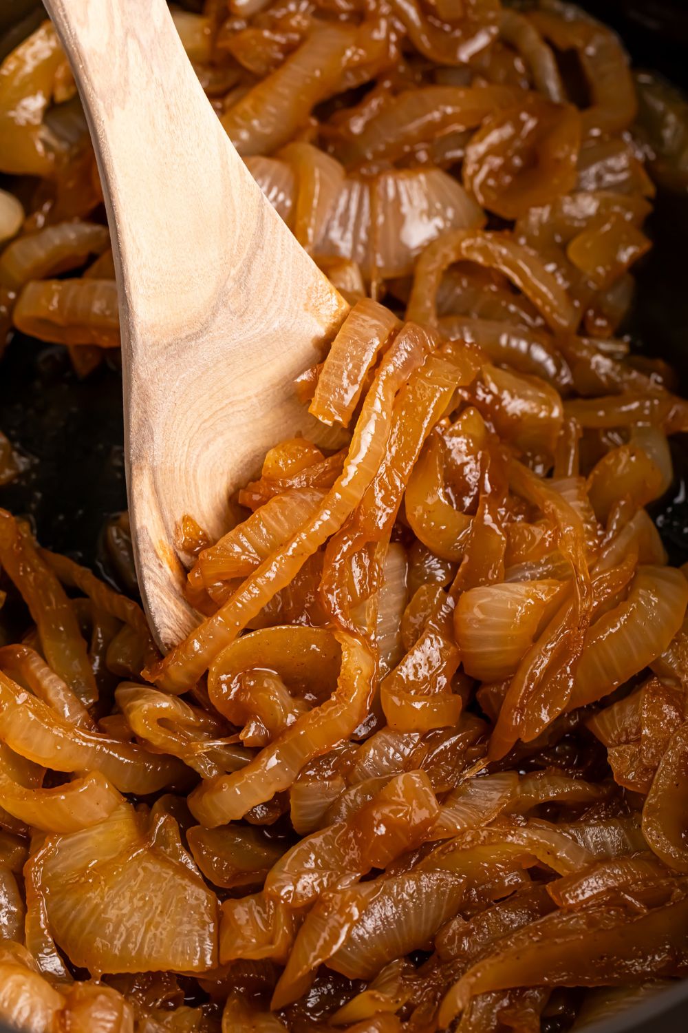 CrockPot Caramelized onions being stirred with a wooden spoon