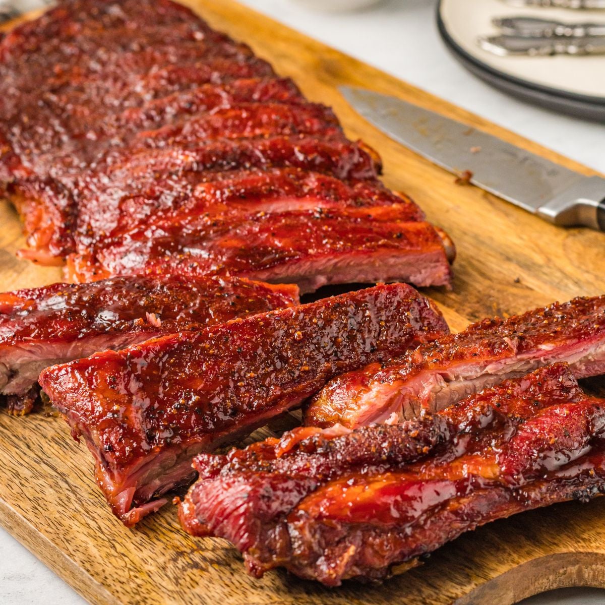 Grilled BBQ Baby Back Ribs placed on cutting board with part of them cut