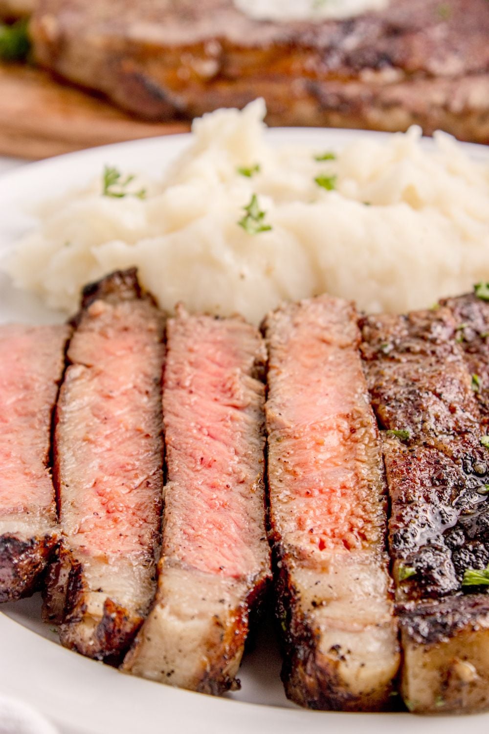 Grilled Ribeye Steaks sliced into strips showing the doneness of steak, and a side of mashed potatoes