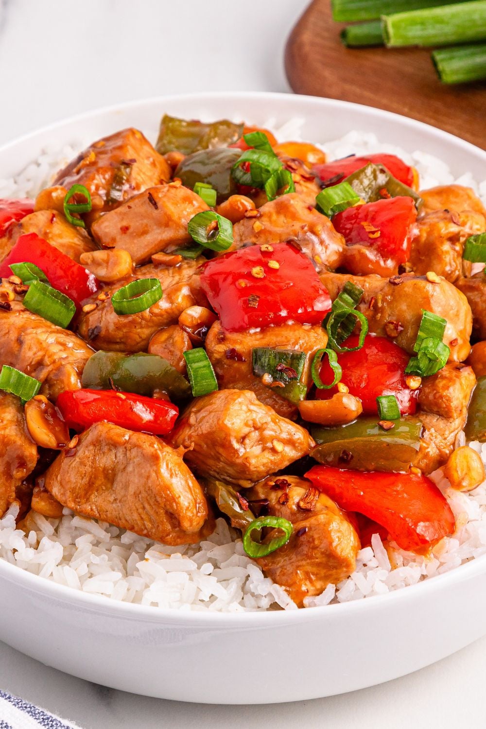 Better Than Takeout Kung Pao Chicken on top of a bed of rice in a white bowl sitting on table