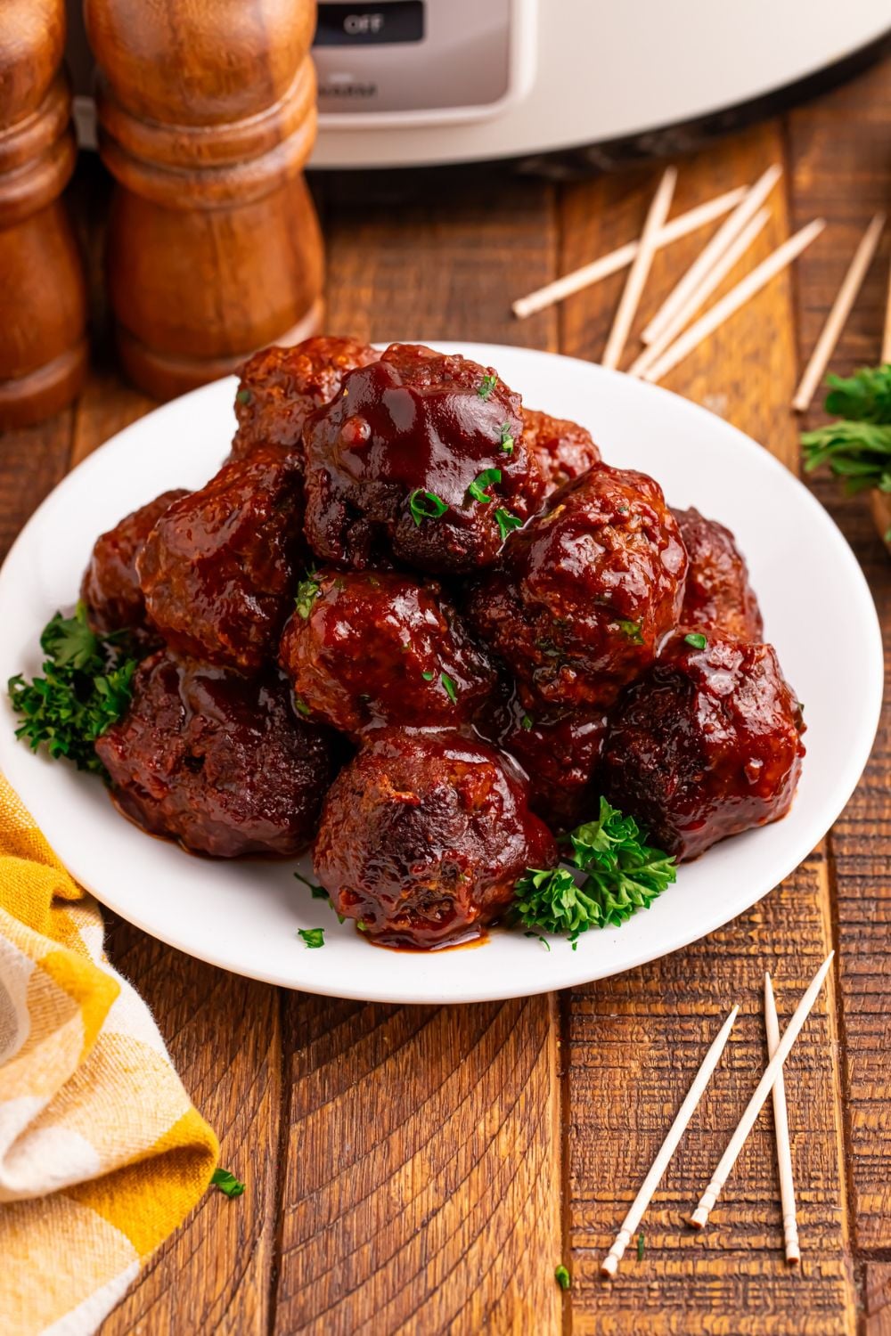 Crockpot Homemade BBQ Meatballs sitting on a plate with toothpicks around table and salt and pepper shaker to side