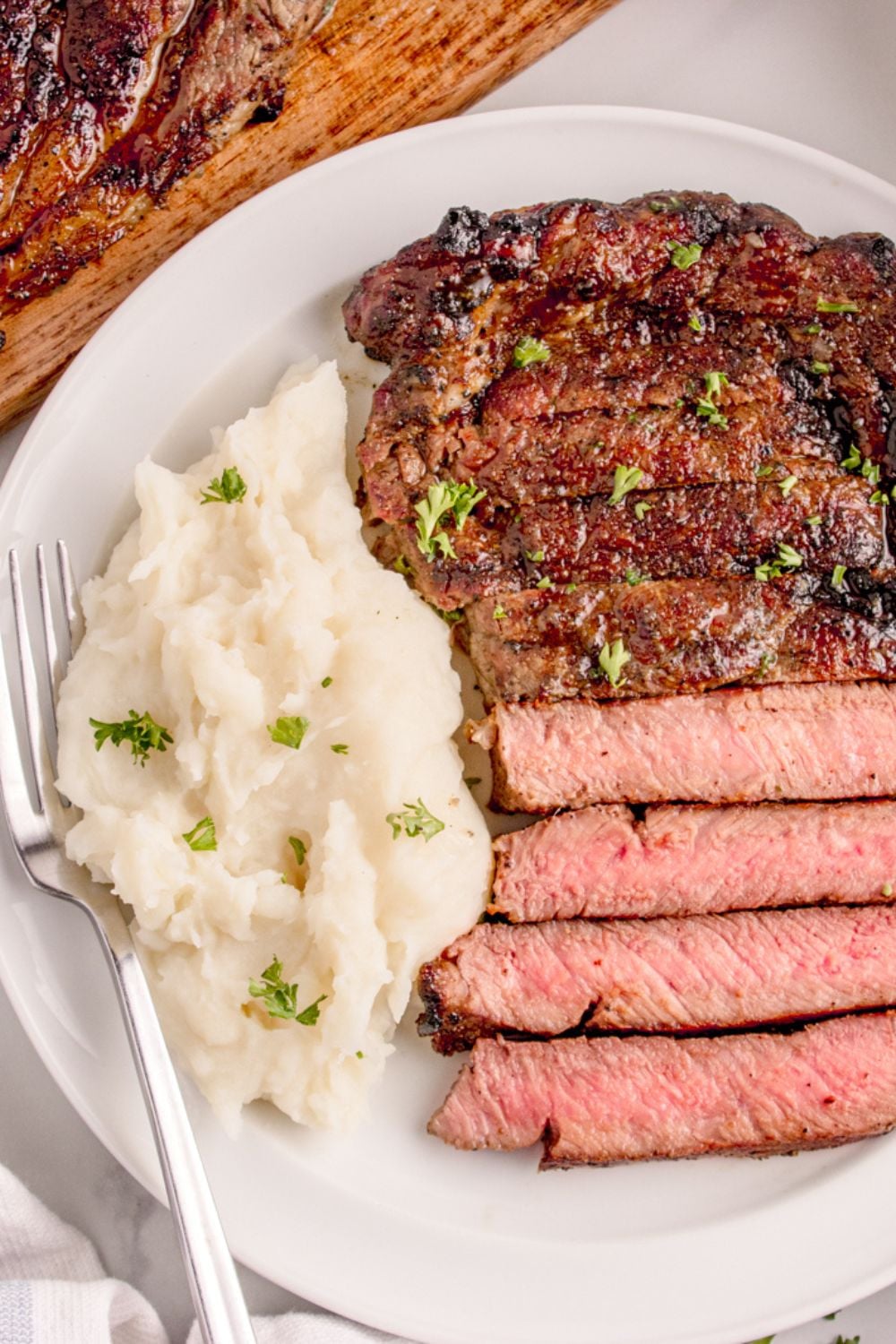 Grilled Ribeye Steak on plate with mashed potatoes to side and a fork on side of plate