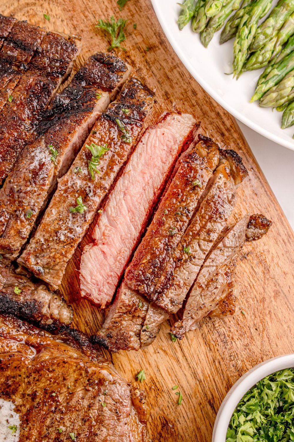 Grilled Ribeye Steaks cut into strips on table with one slice showing how done the steak is