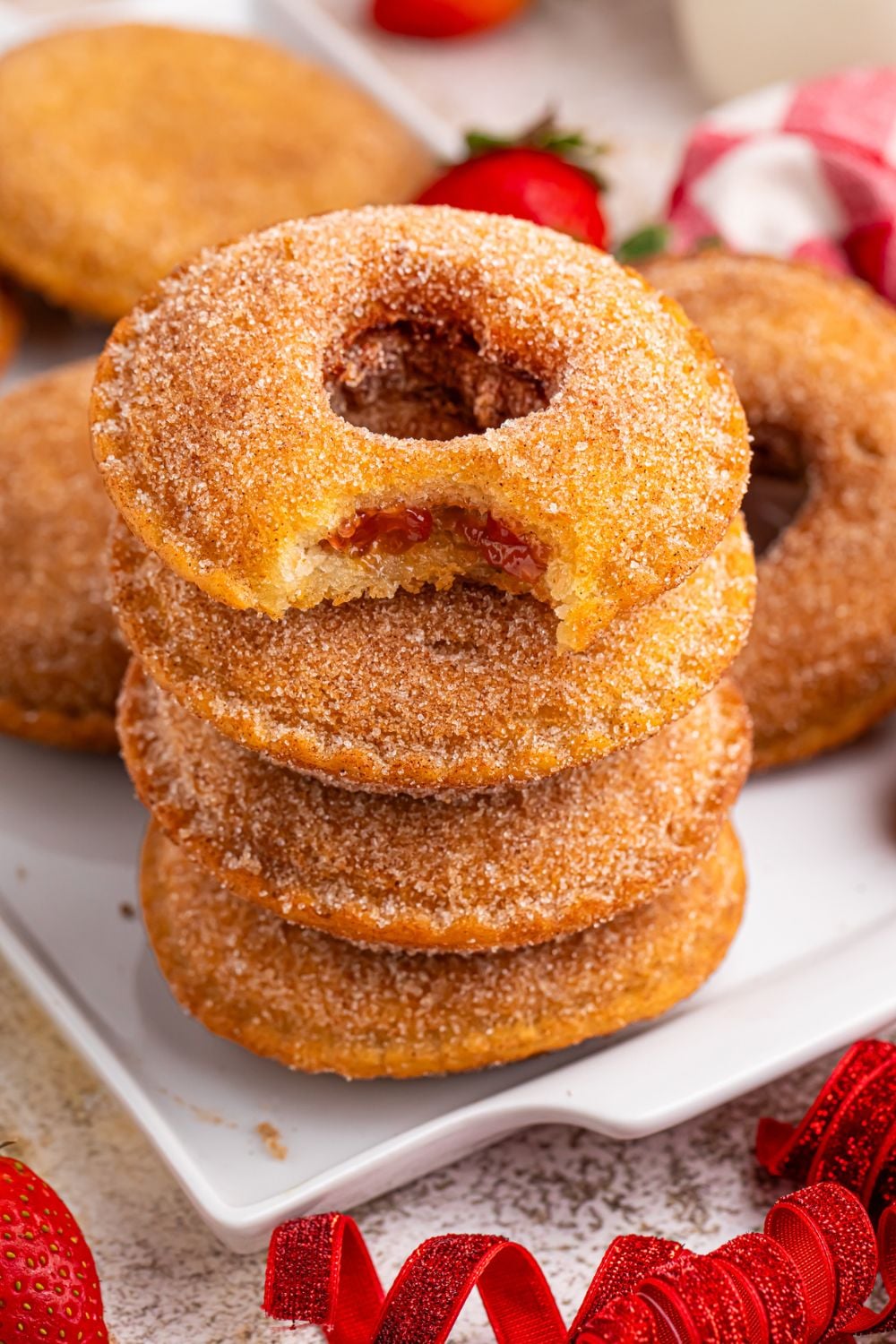 stack of Fried Strawberry Uncrustables that have been fried on table with heart shapes cut out in each of the centers stacked on table 