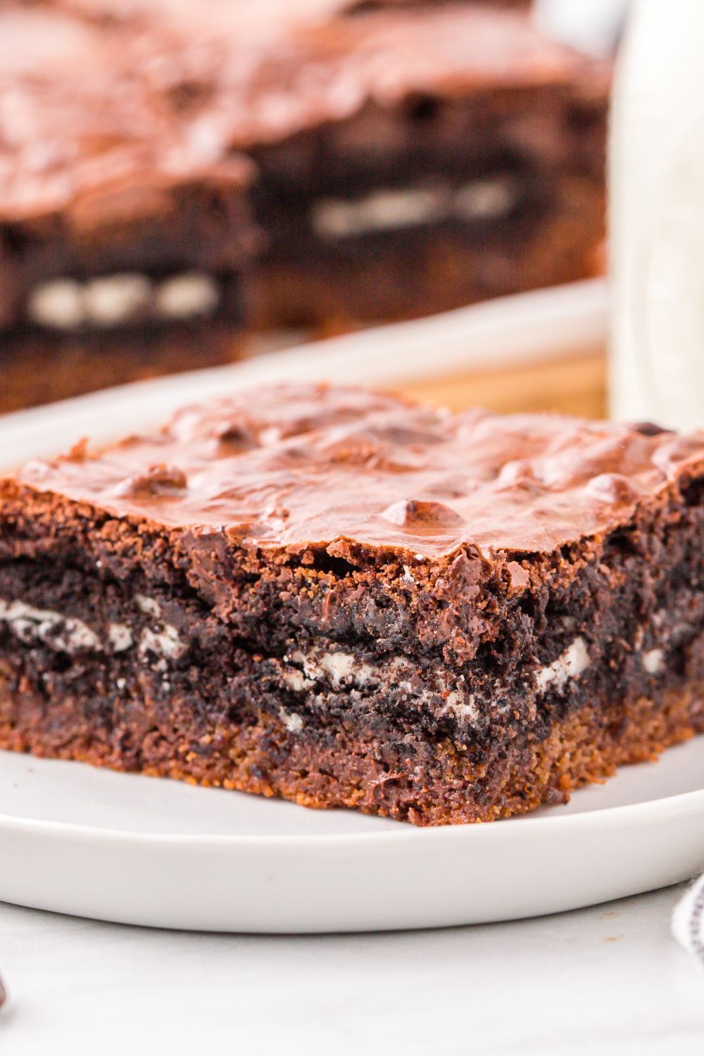 Slutty Brownies sliced on a tray and a plate with cookies on plate with a glass of milk