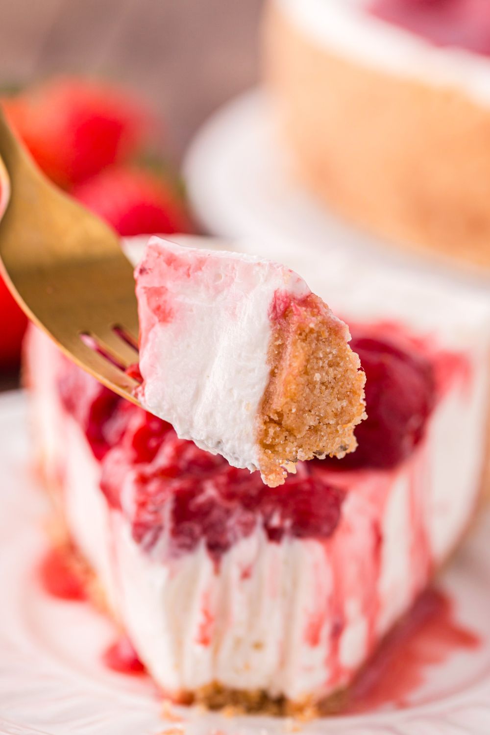 slice of No Bake Strawberry Cheesecake on plate with a fork with a bite on it