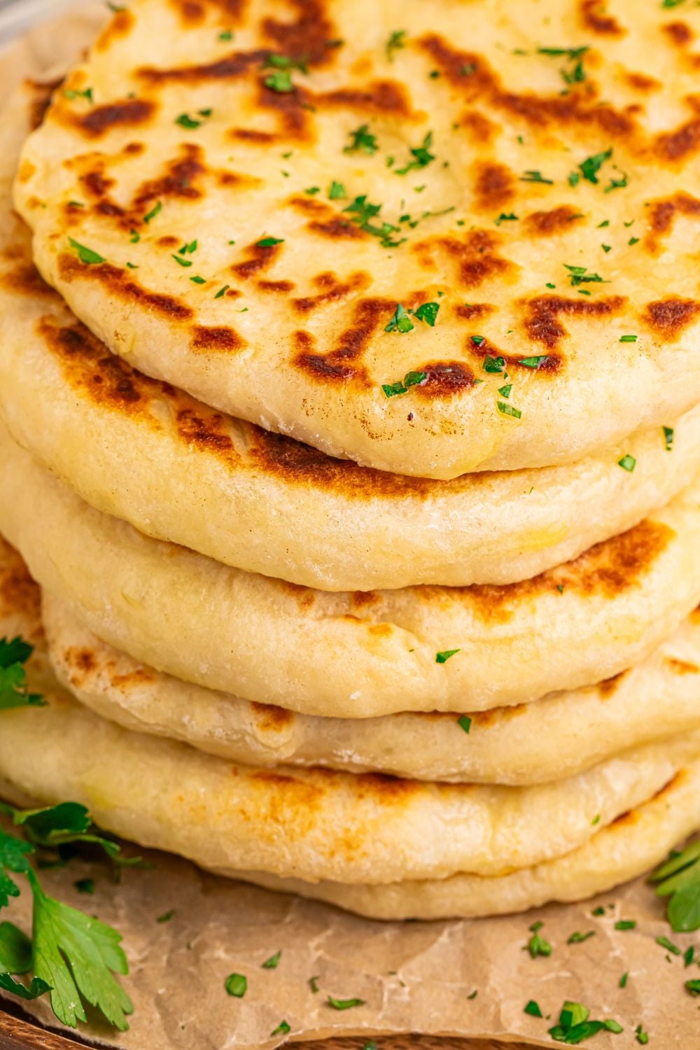 3 Ingredient Flatbread in a stack on a tray with parsley chopped sprinkled around table