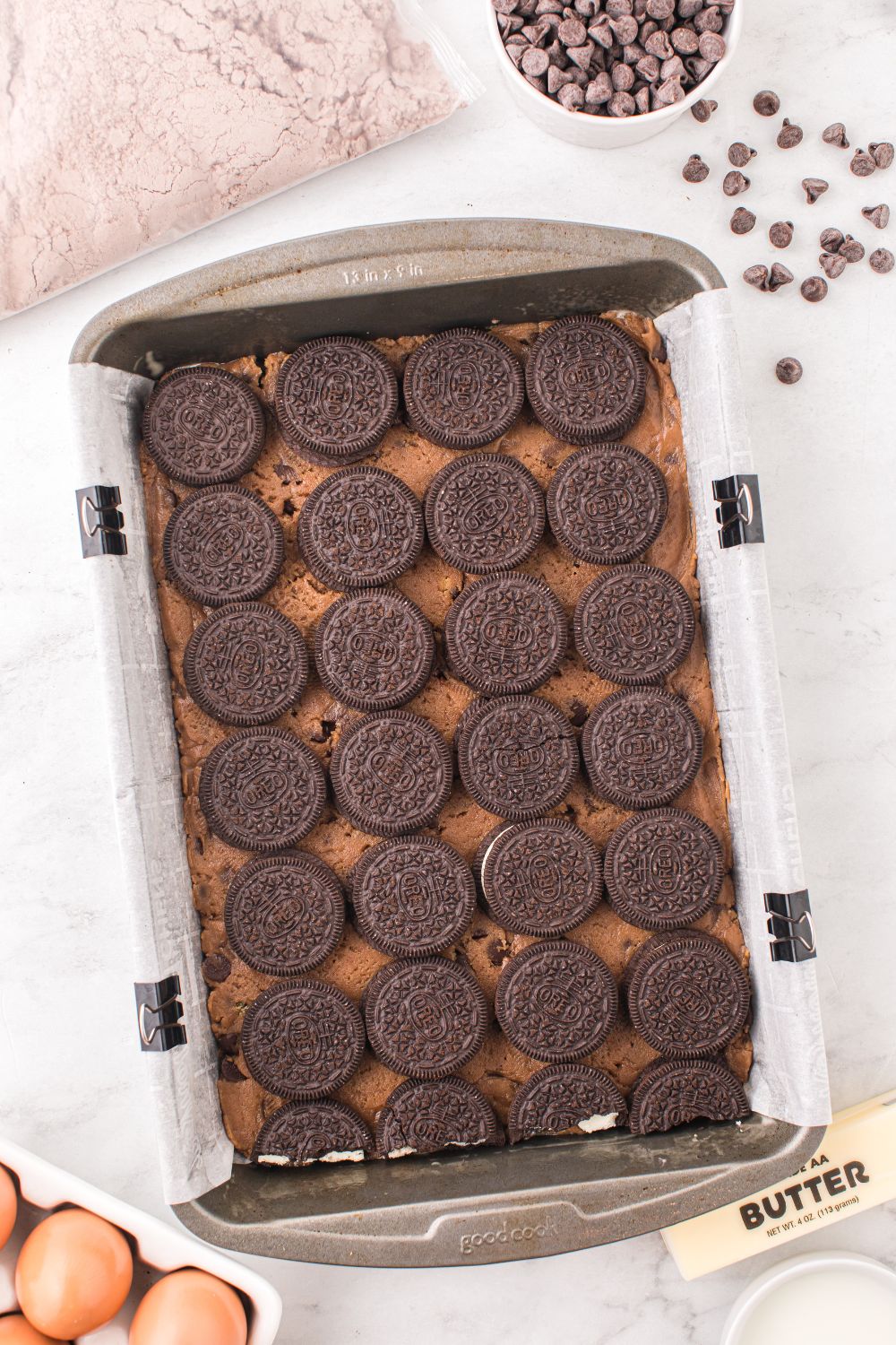 chocolate chip cookie dough topped with Oreo cookies on top in a baking tray 