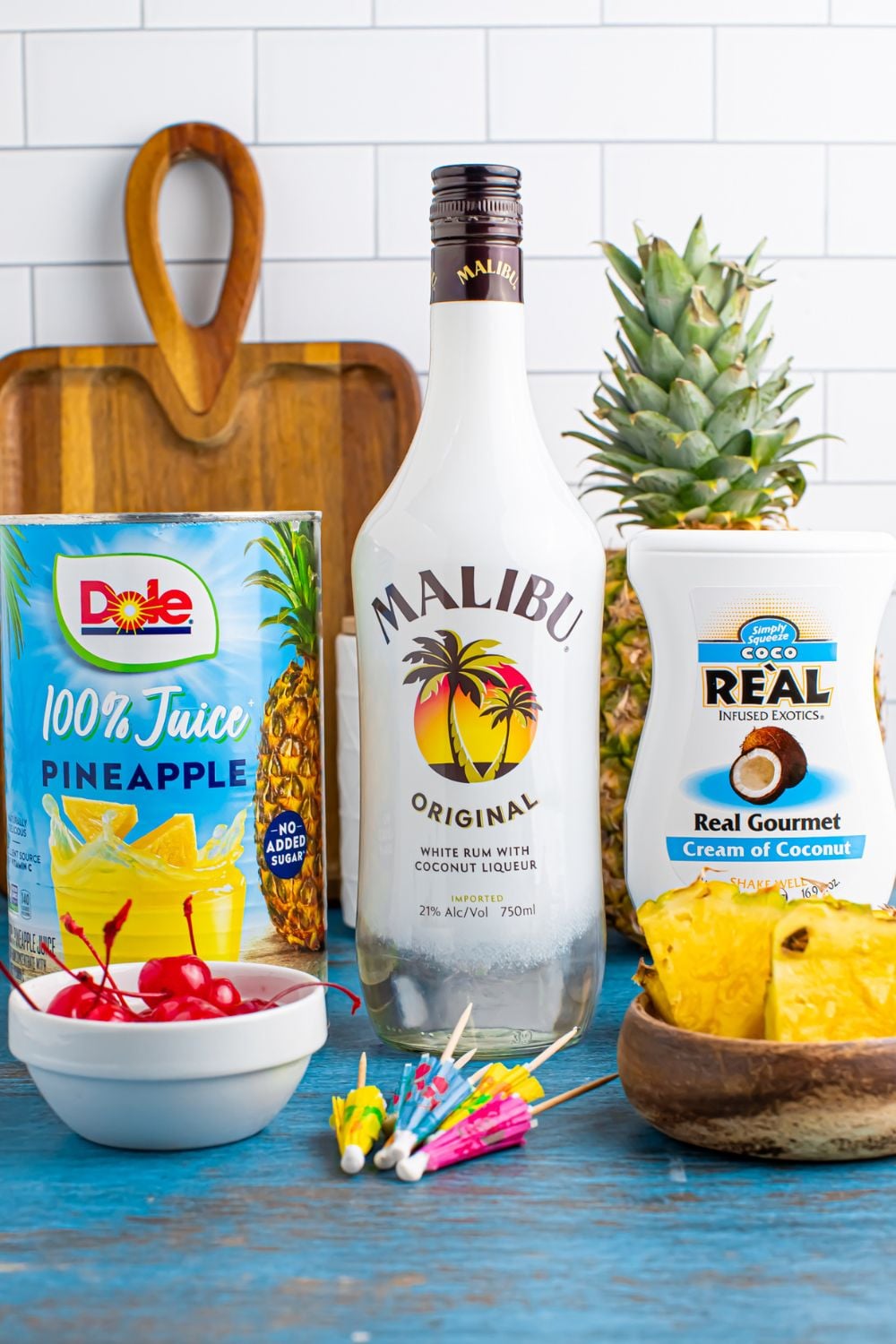 ingredients to make Frozen Malibu Piña Colada sitting on table with a cutting board sitting on table 