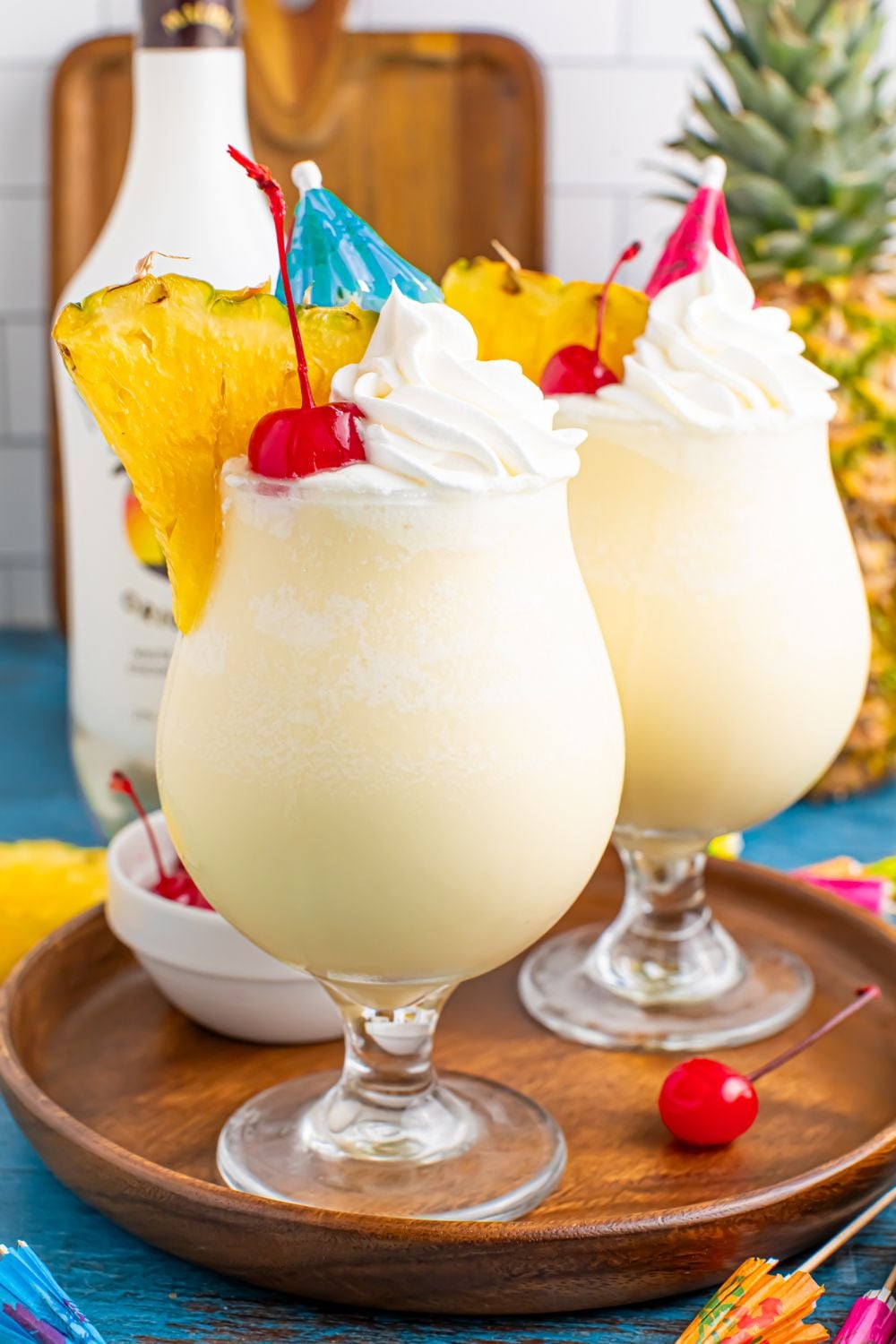 Frozen Malibu Piña Coladas on table with two drinks and a bottle of rum