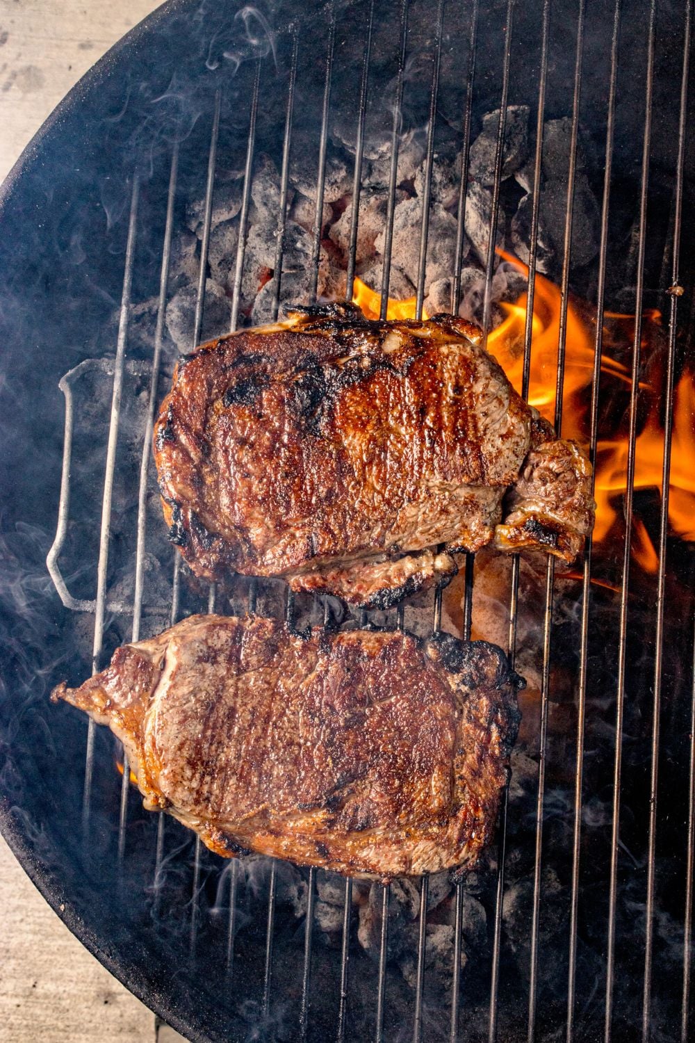 Grilled Ribeye Steaks cooking on a charcoal grill