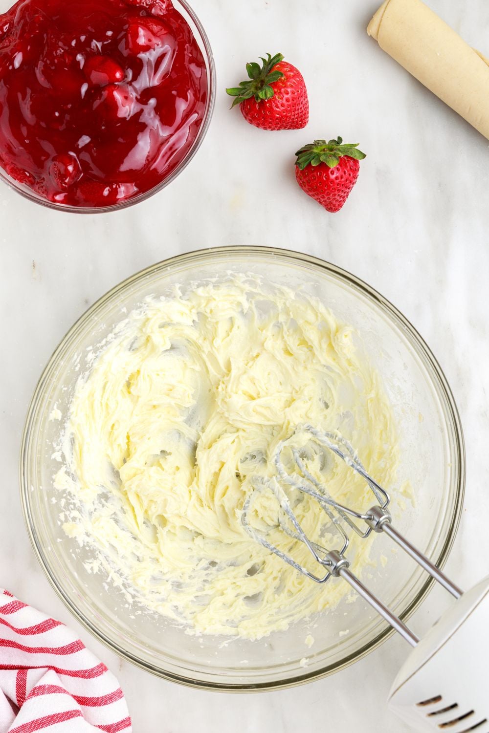 cream cheese filling being mixed up with a hand mixer on table for making Deep Fried Strawberry Cheesecake Pies