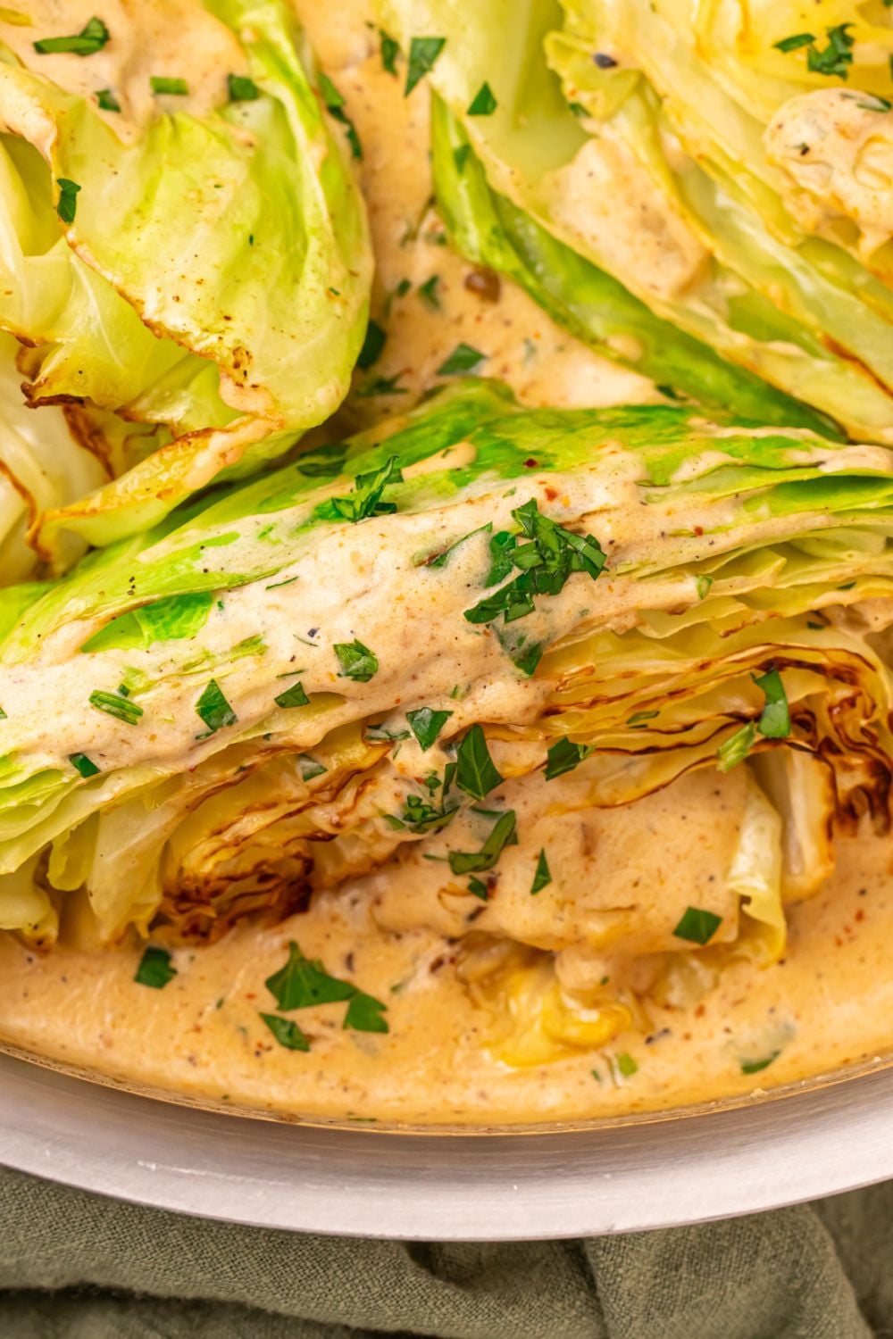 Creamy Garlic Parmesan Cabbage in a skillet coated with sauce and parsley 