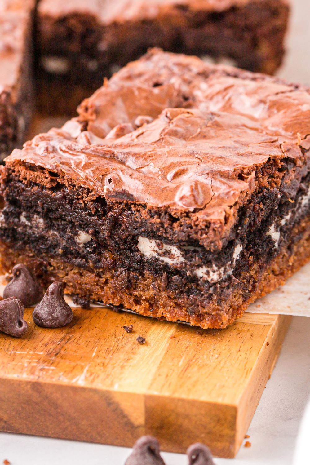 wooden table with Slutty Brownies spread out on tray and a few chocolate chips to the side 