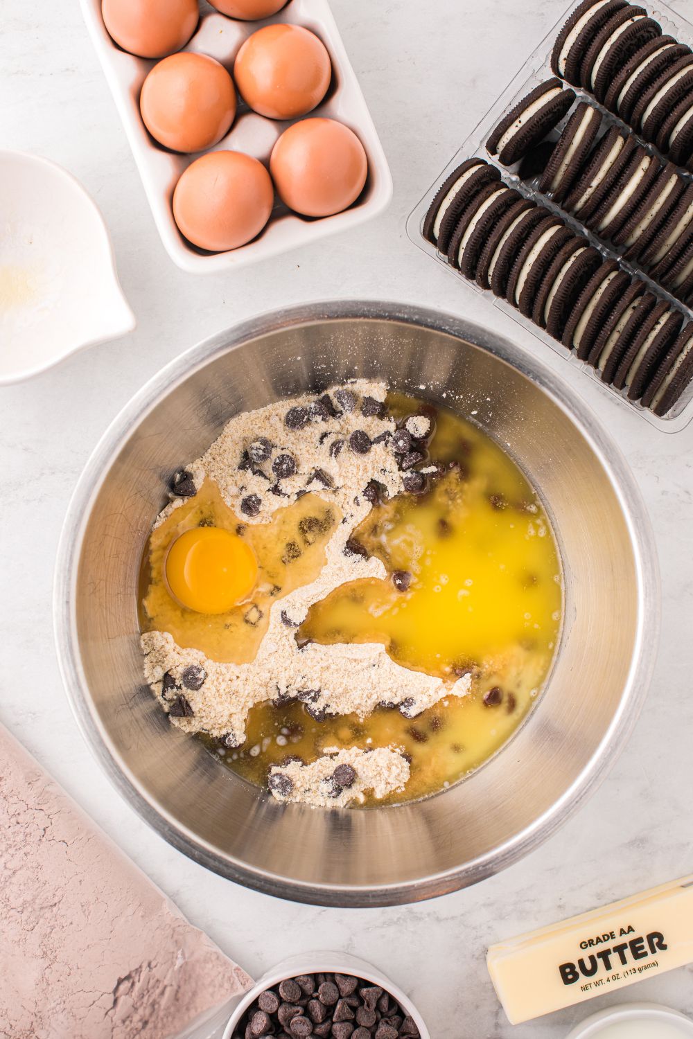 mixing bowl with chocolate chip cookie dough in a bowl with cookies and eggs 