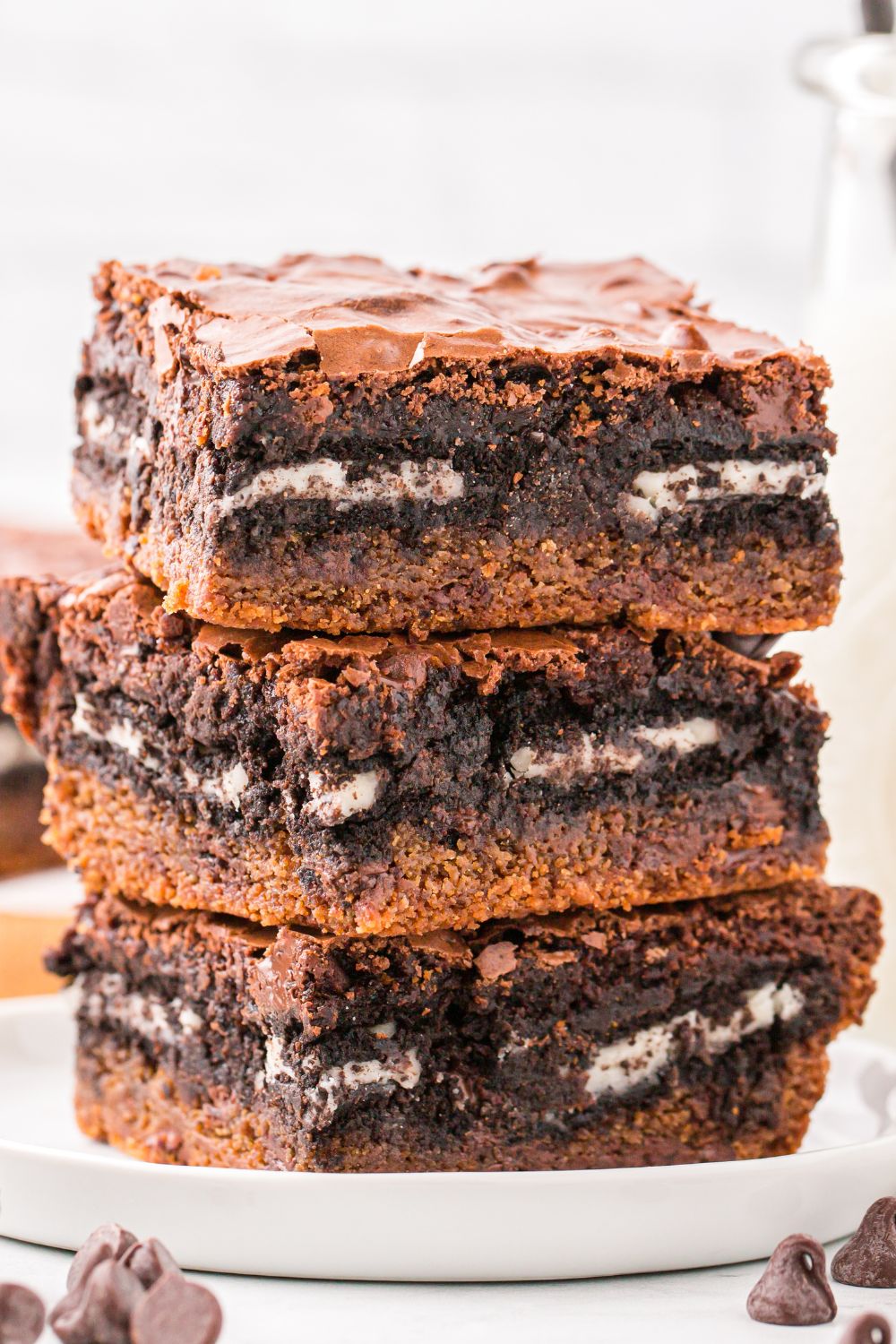 Slutty Brownies stacked on plate with some chocolate chips around table 