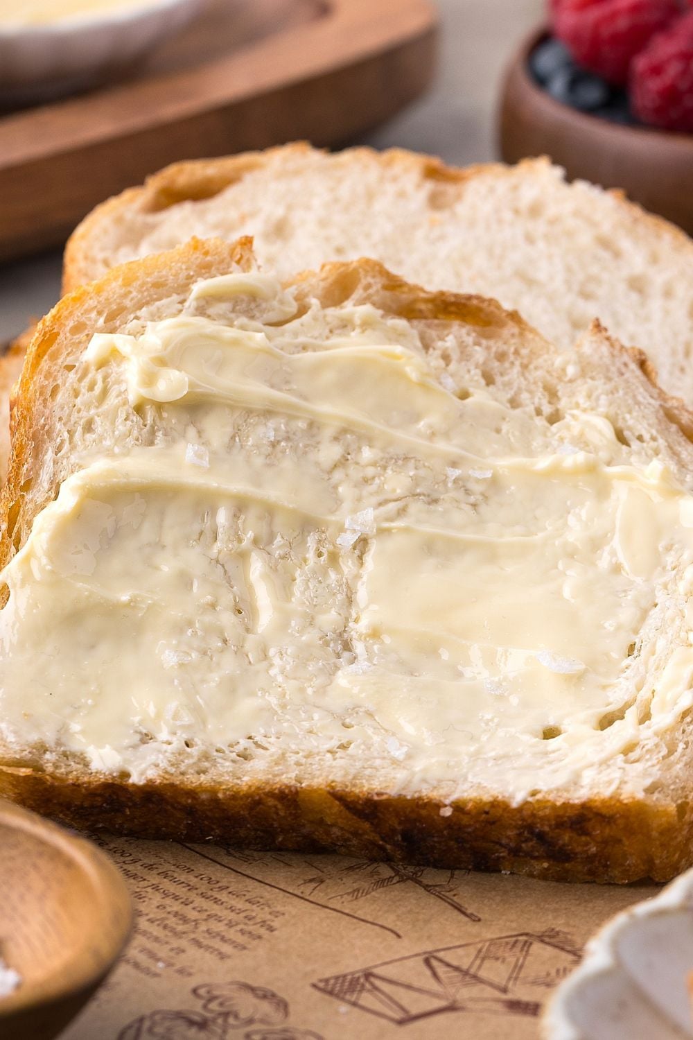 sliced Homemade Sourdough Bread with butter on top of the bread sitting on table 